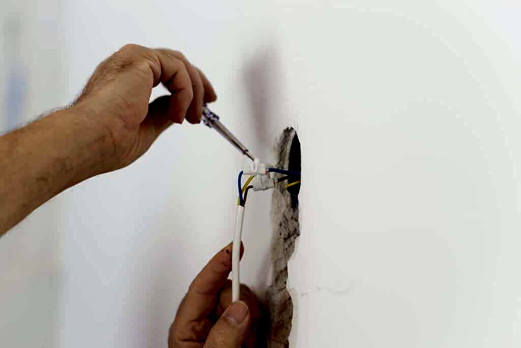 Electrician checking the presence of electrical current in a wire circuit in a home