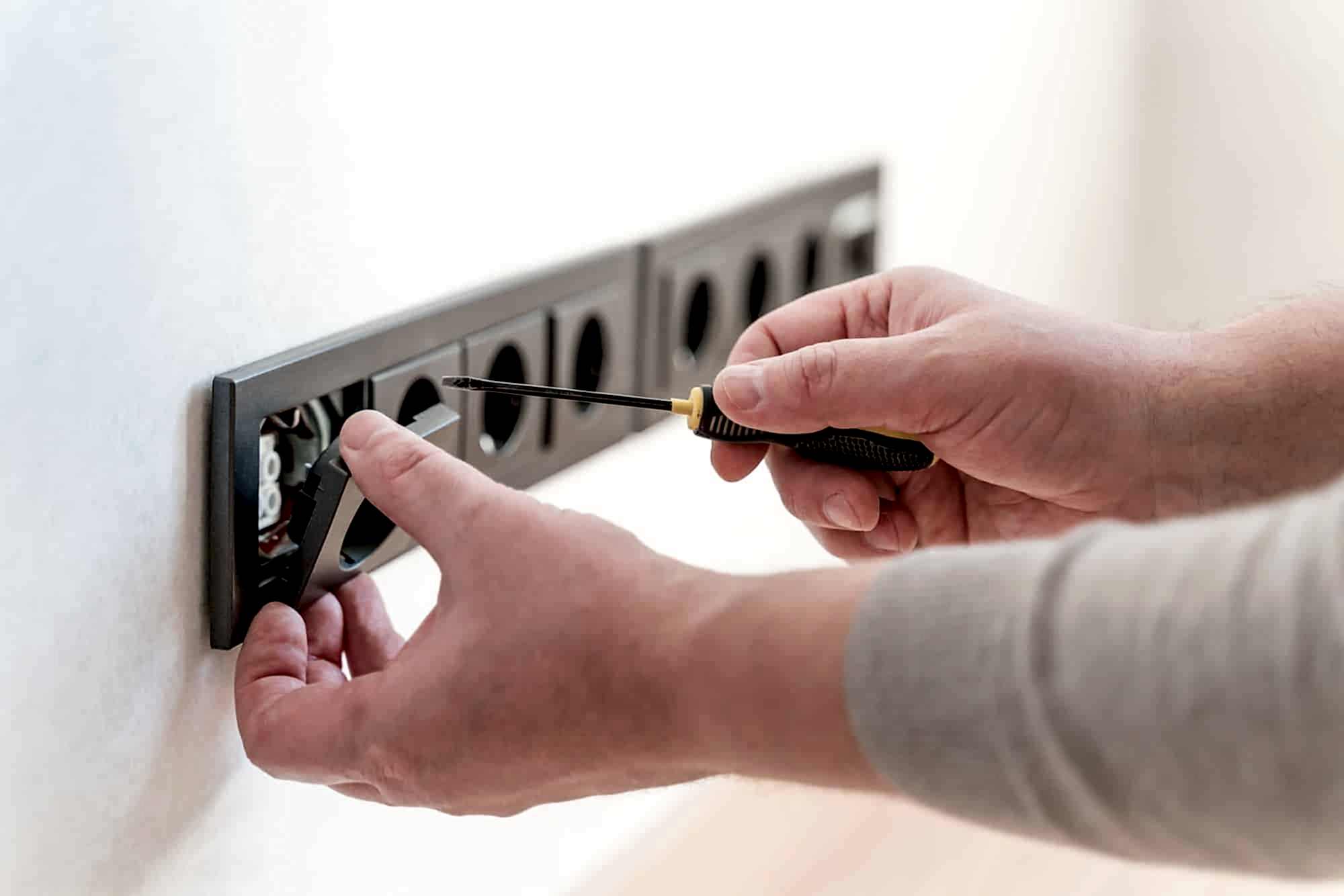Electrician installs sockets in the wall of a new apartment